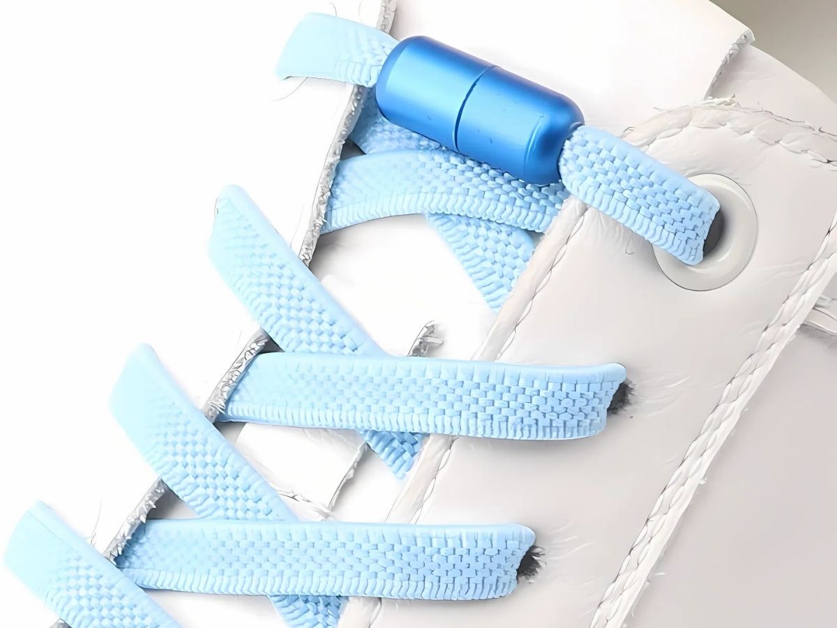 Blauwe natuurlijke look platte elastische veters zonder strikken met draaicapsule, geveterd in een witte sneaker - voegt een leuke kleur toe aan je schoenen